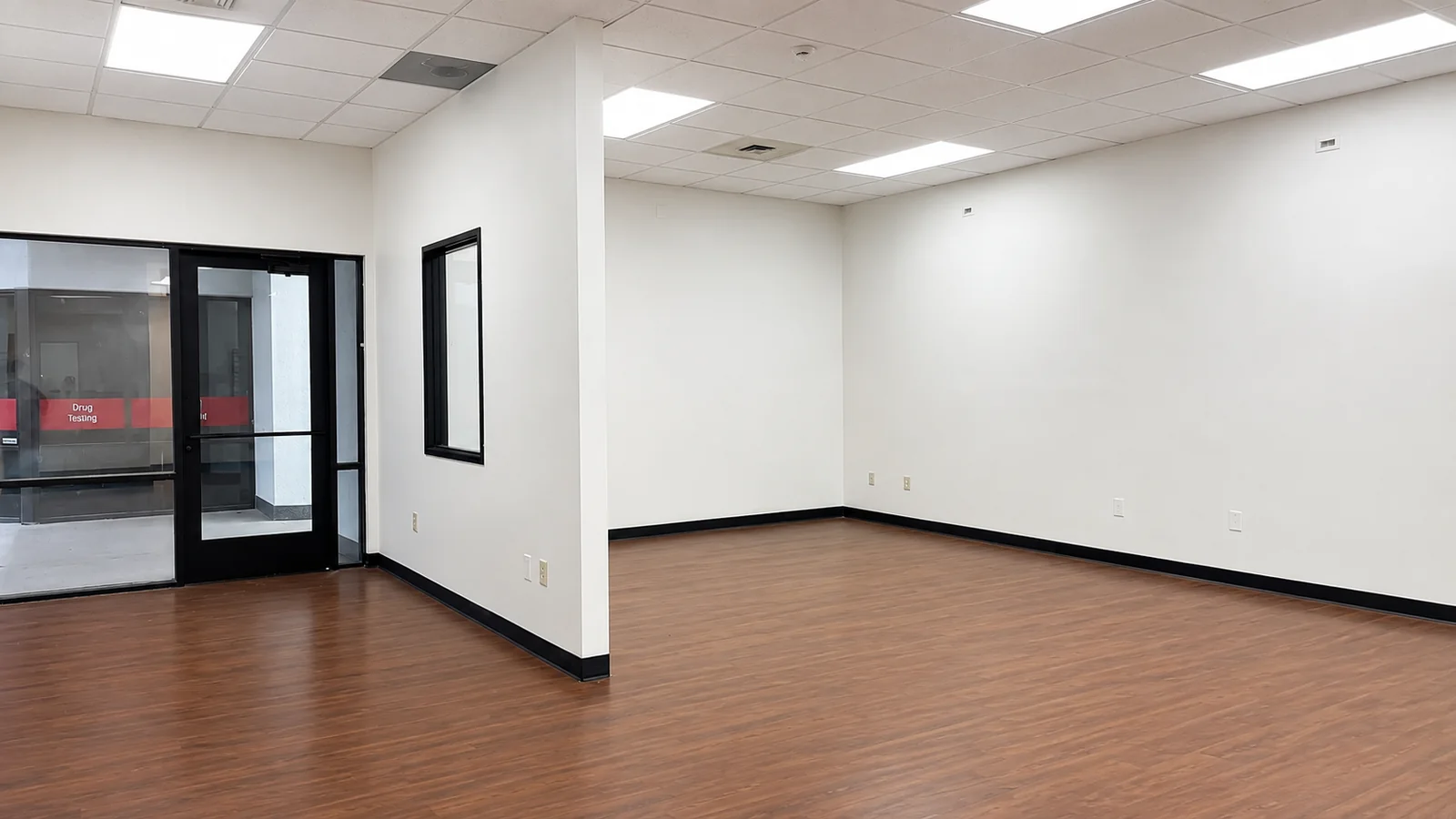 Open work area inside Suite 101B with LED panel lights and a glass entry door
