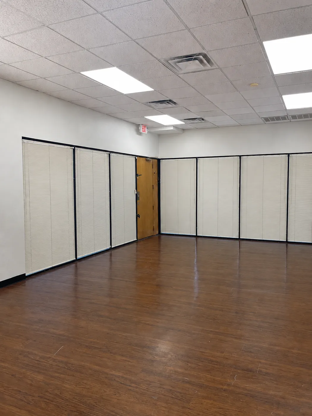 Large open room in Suite 100B with glass office fronts and wood flooring