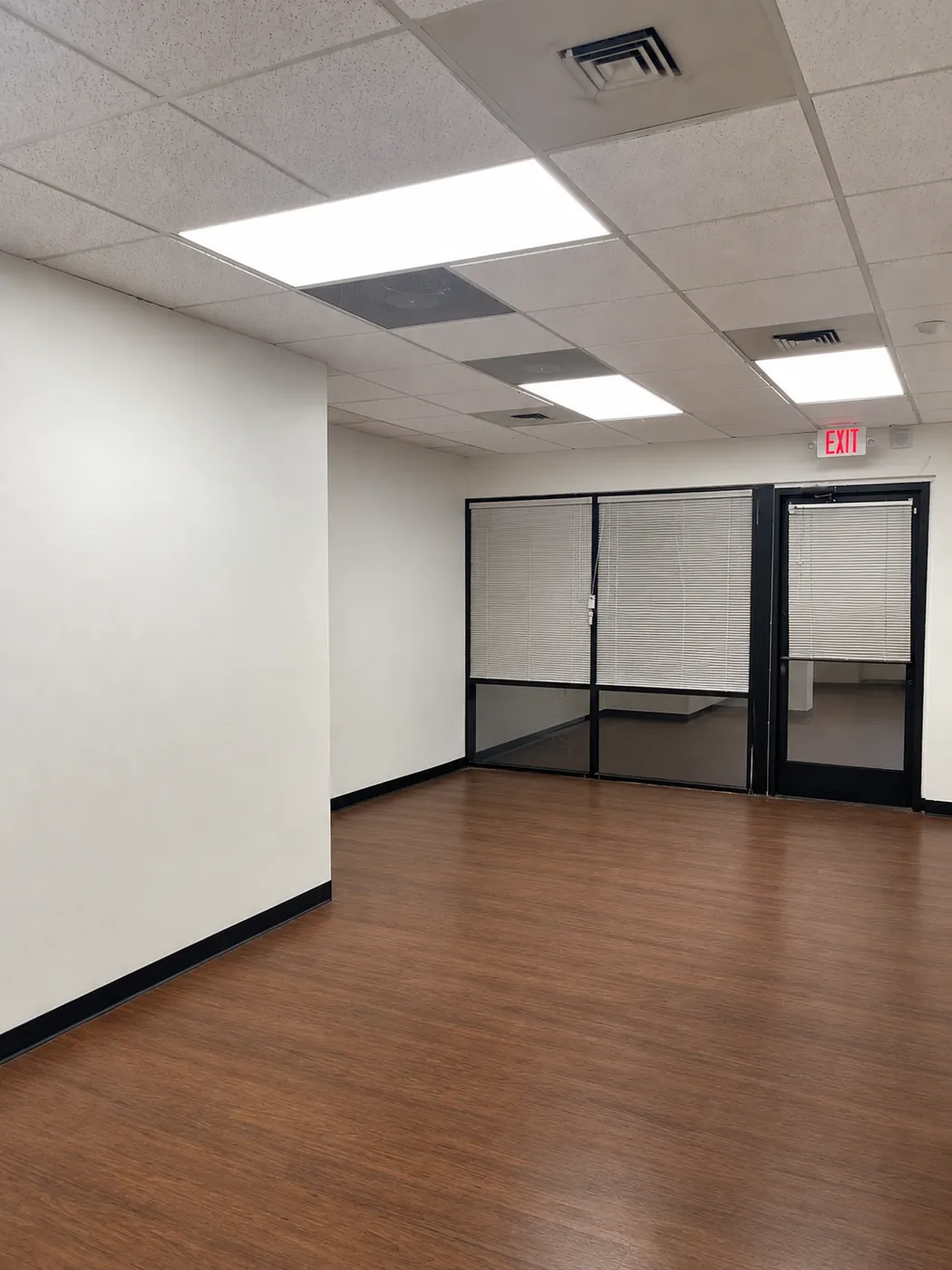 Front room of Suite 103B with glass-front offices and dark wood flooring
